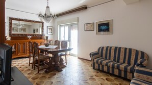 A dining area with a wooden table and chairs, a chandelier, a sofa, and a large mirror. - Apartment 'tra mare e montagna' with Mountain View, Terrace & Balcony (Gaggi)