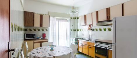 Una cocina con mesa, sillas, microondas, horno y armarios.