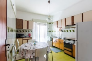 A kitchen with a dining table, chairs, a microwave, an oven, and cabinets.
