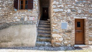 Un bâtiment en pierre avec une porte en bois, un escalier menant à l’entrée et une enseigne indiquant la direction de l’« APARTMENTI ».