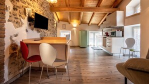 Un intérieur rustique avec des murs en pierre apparentes, des poutres en bois, un coin cuisine et des meubles modernes.