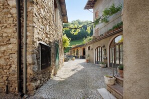 Una estrecha calle adoquinada bordeada por edificios de piedra con ventanas arqueadas y balcones.