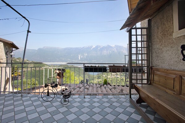 Un balcón con vistas a montañas, un banco de madera y una bicicleta.
