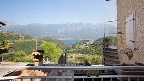Une terrasse offrant une vue sur les montagnes et un lac, des murs en pierre et des plantes en pot.