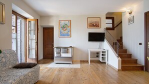 Un salon avec un canapé, un téléviseur, un escalier et un plancher en bois.