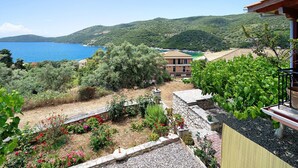 A coastal view with a garden, a building with a tiled roof, and a clear blue sea. - Vardia Studio B: Sea View, Balcony, and Wi-Fi Close to the Beach (?e???da)