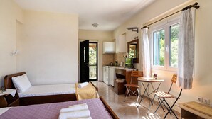 A bedroom with two beds, a desk, a chair, and a small kitchenette. - Vardia Studio B: Sea View, Balcony, and Wi-Fi Close to the Beach (?e???da)