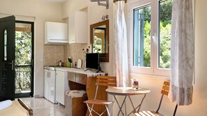 A compact kitchen with a dining area, a small table, and a chair. - Vardia Studio B: Sea View, Balcony, and Wi-Fi Close to the Beach (?e???da)