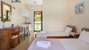 A hotel room with a wooden desk, a bed with a rolled towel, a painting on the wall, and a view through an open door. - Vardia Studio A Holiday Apartment with Sea View, Wi-Fi & Balcony (?e???da)