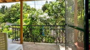 A balcony with a wooden pergola, a metal railing, and a view of lush greenery and white flowers. - Vardia Studio A Holiday Apartment with Sea View, Wi-Fi & Balcony (?e???da)