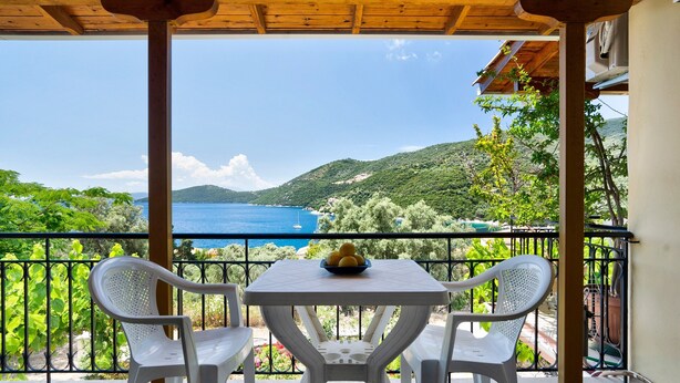 A balcony with a table and chairs, overlooking a scenic view of a body of water and hills. - Vardia Studio A Holiday Apartment with Sea View, Wi-Fi & Balcony (?e???da)