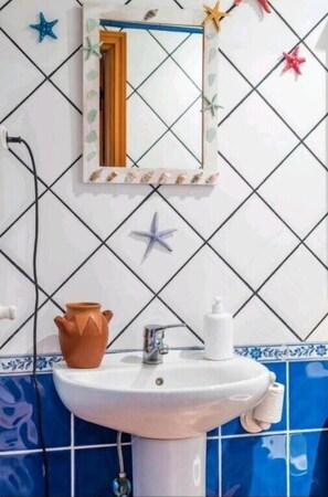 A bathroom with a white sink, a mirror, and decorative starfish on the wall. - Vacation Home "Silence Cave Rural House" with Moutain View, Terrace & Wi-Fi (Artenara)