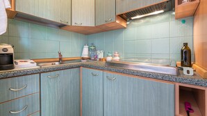 Una cocina con armarios de madera, encimera de granito, pileta de acero inoxidable y microondas.