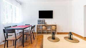A dining area with a table, chairs, a television, and a shelf with baskets. - Apartamento Residencial Limonar with A/C & Wi-Fi (Málaga)