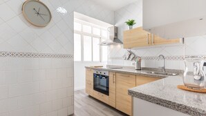 A modern kitchen with white tiles, wooden cabinets, a built-in oven, and a stainless steel sink. - Apartamento Residencial Limonar with A/C & Wi-Fi (Málaga)