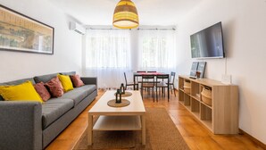 A living room with a sofa, a dining table, a TV, and a wooden cabinet. - Apartamento Residencial Limonar with A/C & Wi-Fi (Málaga)