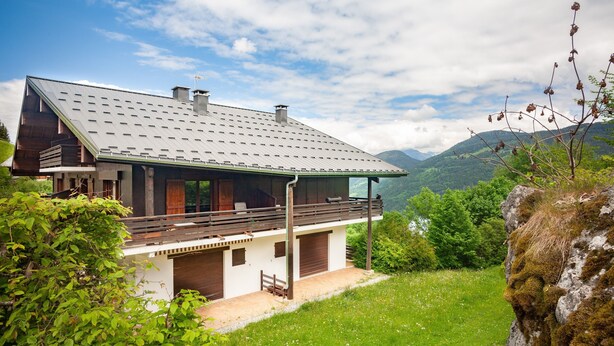A modern house with a sloped roof, wooden balcony, and a view of green hills. - Apartment at "Chalet Jade" with Mountain Views, Balcony, and Wi-Fi (Saint-Gervais-les-Bains)