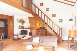 A living room with a wooden staircase, a sofa, a coffee table, and a television.