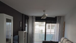 A living room with a sofa, a TV, a dining table, and a ceiling fan. - Apartment 'Alegria' near the Beach with Shared Pool (Garrucha)