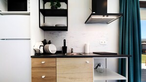 Eine moderne Küche mit weißen Schränken, einer schwarzen Arbeitsplatte und einem eingebauten Regal über dem Spülbecken.