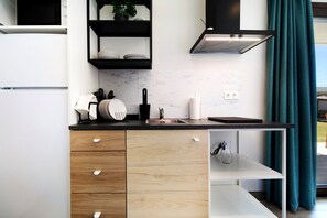 A modern kitchen with white cabinets, a black countertop, and a built-in shelf above the sink.
