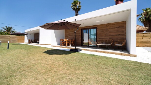 Ein modernes Haus mit Terrasse, Gartenmöbeln und einer Holzfassade.
