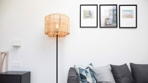Ein modernes Wohnzimmer mit einem grauen Sofa, einer Stehlampe und drei gerahmten Bildern an der Wand.
