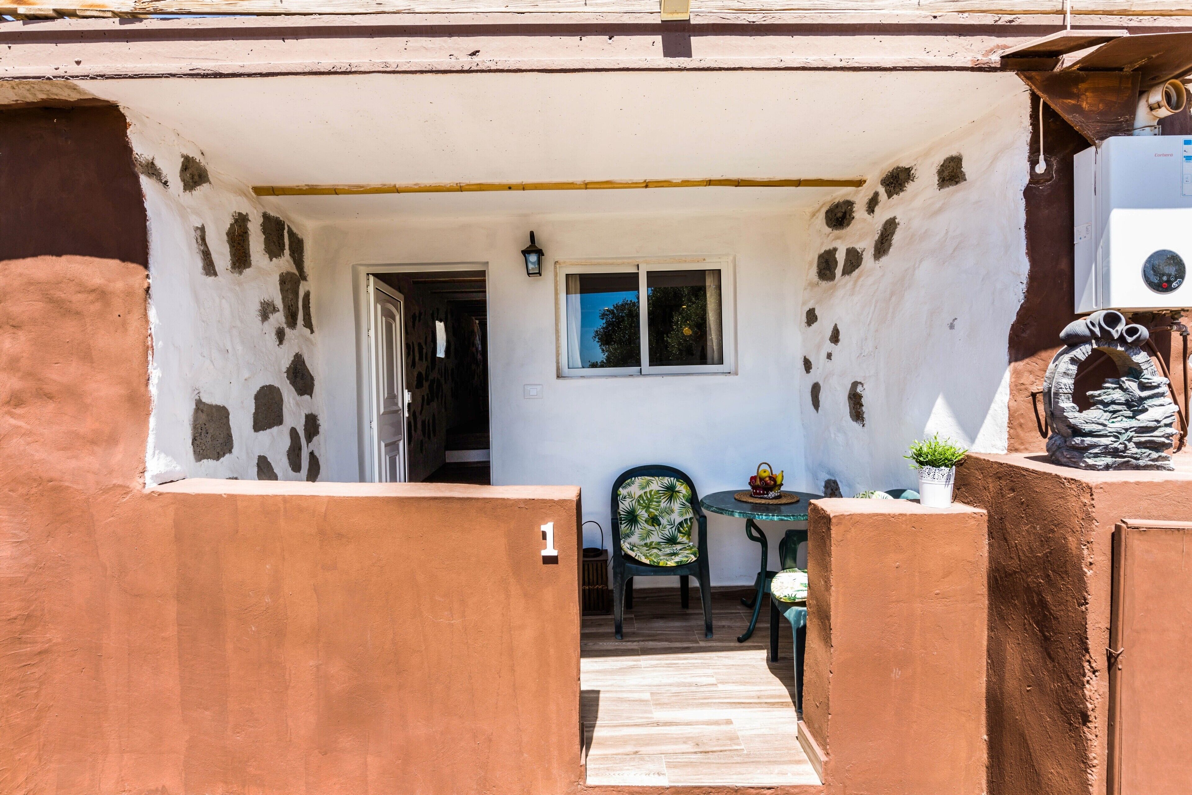 A narrow entrance with a door, a small table with chairs, and a potted plant.