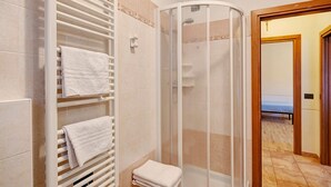 Een badkamer met een douche, een handdoekhouder en een toilet.