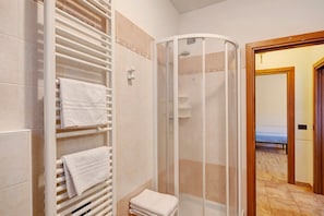 Un baño con ducha, toallero y retrete.