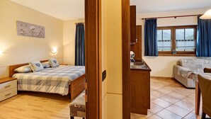 Een slaapkamer met een bed, nachtkastjes, een bureau en een raam met gordijnen.