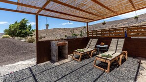 A covered outdoor seating area with wooden furniture and hanging planters. - Holiday Apartment "La Fortaleza - Casa La Fuentita - Adults Only" with Mountain Views (La Fuentita)