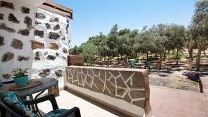 A balcony with a stone wall, a potted plant, and outdoor furniture. - Holiday Home 'Esencia Eco-rústico - Adults Only' with Shared Pool and Garden (La Fuentita)