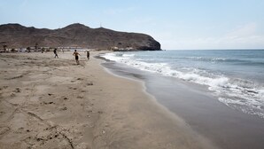 A beach with a sandy shore, waves, and a mountain in the background. - Holiday Home 'Esencia Eco-rústico - Adults Only' with Shared Pool and Garden (La Fuentita)