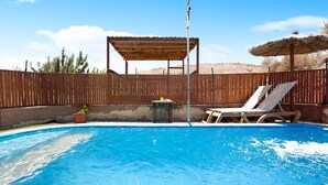 A swimming pool with a wooden deck, a covered seating area, and a potted plant. - Adults-Only Holiday Home Alma Eco-Rustic with Shared Pool and Terrace (La Fuentita)