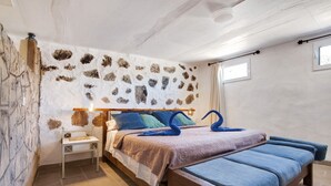 A bedroom with a stone wall, a bed with blue and brown bedding, a wooden headboard, and a small bedside table. - Adults-Only Holiday Home Alma Eco-Rustic with Shared Pool and Terrace (La Fuentita)