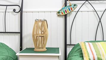 A bed with green bedding, a bedside table with a lamp, and a wall-mounted sign.