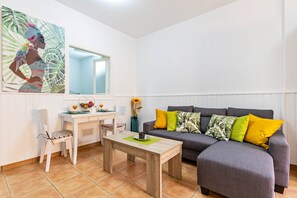 Ein Wohnzimmer mit einem grauen Sofa, einem weißen Esstisch und einem weißen Stuhl.