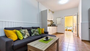 Ein modernes Wohnzimmer mit einer Couch, einem Couchtisch und einer Küche im Hintergrund.