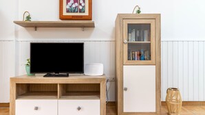 Ein TV-Schrank aus Holz mit einem Flachbildfernseher, einer kleinen Pflanze und einem gerahmten Bild darüber.