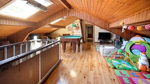 Interior de madera con mesa de billar, zona de juegos y televisor.