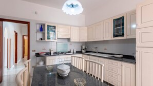 Eine moderne Küche mit weißen Schränken, einer Arbeitsplatte aus Granit und einem Essbereich mit weißem Tisch und Stühlen.