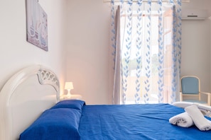 A bedroom with a bed, a chair, a nightstand, and a window with curtains.