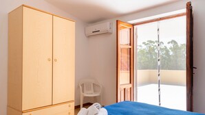 Une chambre dotée d’un lit, d’une armoire, d’un climatiseur, d’une chaise et d’un balcon avec vue.