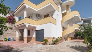 Un immeuble résidentiel à plusieurs étages, doté d’une façade incurvée, d’un garage et de plantes en pot dans la cour.