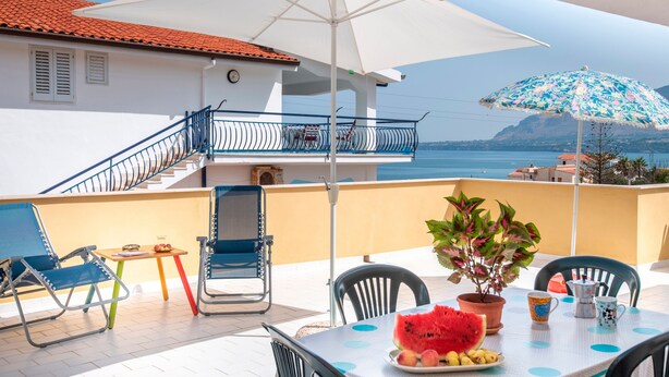 Un balcon avec une table, des chaises et un pot de fleurs.