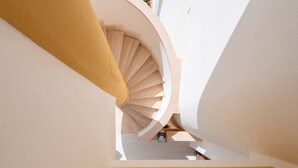 Un escalier en colimaçon dans un bâtiment dont l’intérieur est blanc et un des murs est jaune.