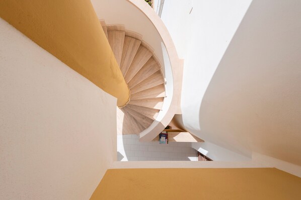 A spiral staircase in a building with a white interior and a yellow wall. - Casa Viola Apartment with Sea View, Terrace and Wi-Fi (Trappeto)