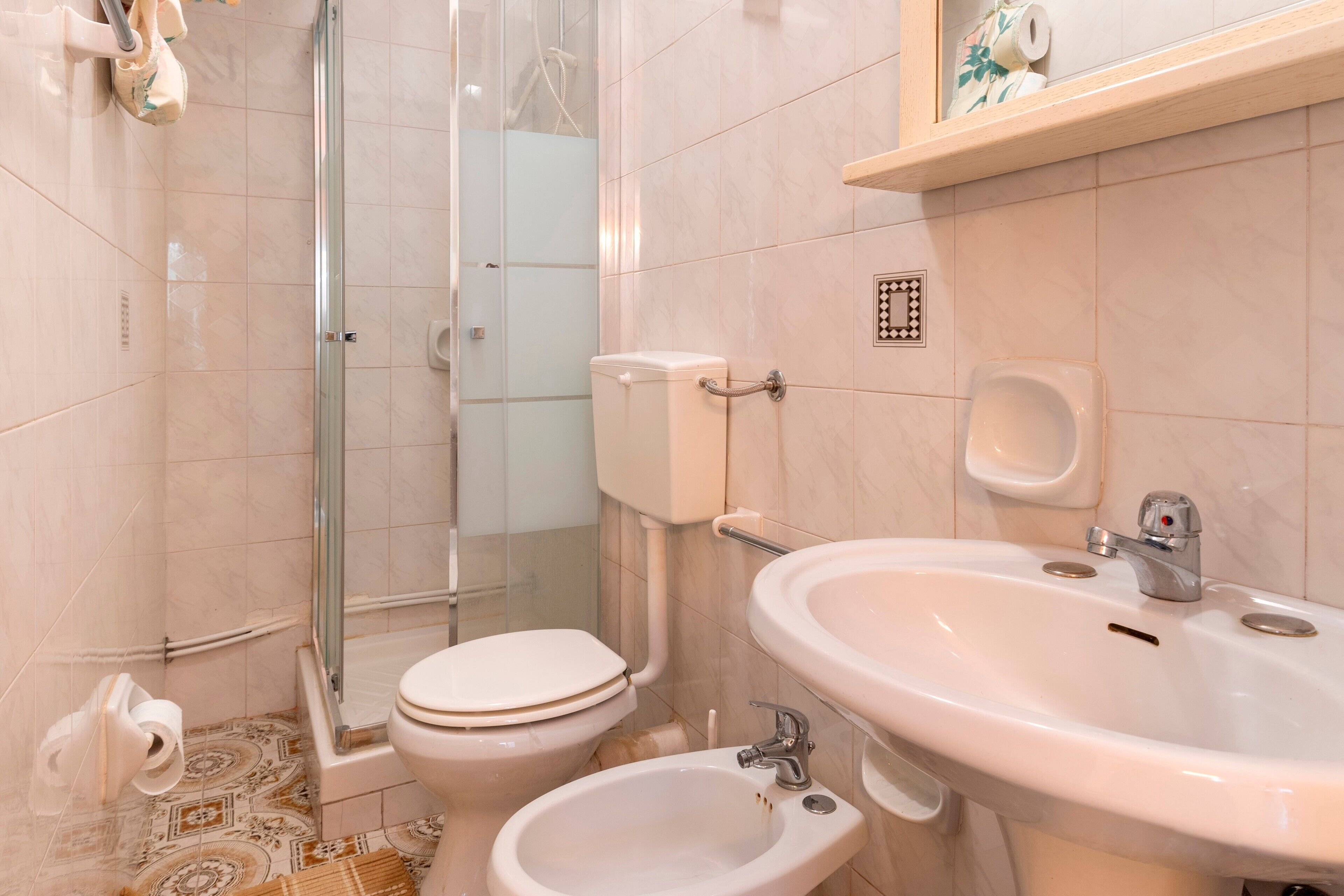 A bathroom with a toilet, bidet, sink, and shower area.