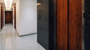 Un couloir avec une porte en bois et un mur en marbre noir.